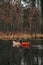 A person paddling a wooden canoe along the beautiful forest lake. Tranquil autumn scene with a man in a boat