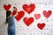 person painting vibrant red hearts on a white brick wall