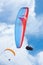 Person, parachute and paragliding in blue sky for flight, stunt and courage with extreme sport. Athlete, glide and