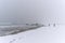 Person photographing a rock on the beach during a windy snowstorm