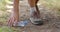 A person picks up a plastic bottle while walking on a dirt path and collecting trash