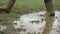 Person with pink boots and blue umbrella splashing in the puddle. girl in raincoat and rubber boots jumping into puddle