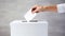 The person places a ballot for the election of president, senator or deputy into a white ballot box.