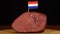 Person placing decorative Dutch flag toothpicks into piece of red meat.