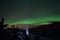 Person pointing flashlight beam towards aurora borealis on winter night sky in spruce tree field