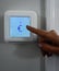 Person pointing to a Euro symbol on a smart thermostat -- heating and cooling cost concept
