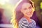 Person, portrait and smile with nature, sunrise and park for happiness and wellness. Woman, joy and bokeh with closeup