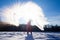 Person pouring hot water up in the sky, sunny winter day. Boiling water challenge, which instantly freezes, turns into snow if the