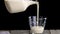 Person pours fermented baked milk from a jug into a glass.