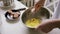Person preparing homemade omelette mixing eggs with hand corolla.