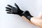 Person put on black latex gloves on white background