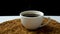 Person putting on table cup of granulated instant coffee among granules on black background.