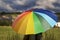 A person with rainbow colored umbrella in the rain