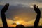 Person raising hands silhouetted against a sunset