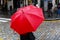 Person with red rain umbrella crosses a city street