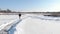 Person rides in white figure skates on frozen lake in winter. Woman is ice skating outdoor on frozen pond. Female is having fun on