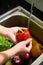 Person rinsing red bell pepper