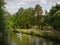 Person rowing a boat full of people on a river surrounded by vegetation and trees