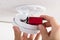 Person`s Hand Inserting Battery In Smoke Detector