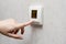 A person& x27;s hand presses the buttons on the smart home control wall sensor. Modern heating and cooling system of the