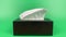 a person\\\'s hand pull out a piece of tissue from tissue paper box isolated on green background.