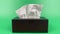 a person\\\'s hand pull out a piece of tissue from tissue paper box isolated on green background.