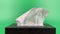 a person\\\'s hand pull out a piece of tissue from tissue paper box isolated on green background.