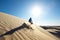 person,sandboarding down sand dunes with clear blue sky in the background