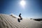 person,sandboarding down sand dunes with clear blue sky in the background