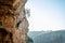 Person is scaling a cliff face, ascending the rock wall with ropes and equipment