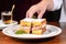 person serving a monte cristo sandwich on a plate