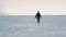 Person silhouette in black clothes walking on frozen snow covered flatlands