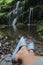 Person sitting alone in the waterfall with relax feet. Self love care and healing moment concept. Relaxation with nature.