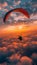 Person soaring over clouds in the orange afterglow of dusk while parasailing