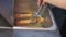 Person sorts delicious natural sausages with tongs in stove