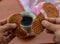 A person is splitting a stroopwafel over a cup of coffee