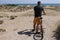 Person stand with back, arriving at his destination after bike ride to rest on beach