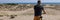 Person stand with back, arriving at his destination after bike ride to rest on beach