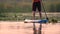 Person stand up paddle board on an inflatable raft and paddles along the river at sunset. Slow motion