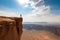 person, standing at the edge of a cliff, overlooking an epic view of a desert landscape