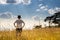 A person standing in large field enjoying the nature under beautiful blue sky