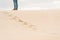 Person standing in sand dunes. Wind blowing sand away