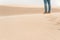 Person standing in sand dunes. Wind blowing sand away