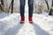 A person standing in the snow wearing red boots created with generative AI technology