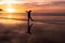 a person standing on top of a beach near water at sunset