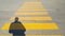 A person stands at the beginning of a pedestrian crossing, where it is written stop and waits for the passage time, on the yellow