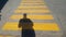 A person stands at the beginning of a pedestrian crossing, where it is written stop and waits for the passage time, on the yellow