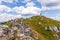 Person stands on a green hilltop against the backdrop of a blue cloudy sky. Big Fatra, Slovakia.