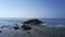 Person stands on rocky cliff top at endless blue ocean