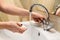 Person starts washing hands, opening water tap with soap in other hand